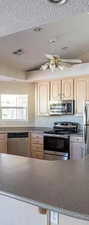 Kitchen with stainless steel appliances, dark stone countertops, and light wood finish cabinets