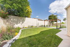 Fenced backyard featuring a pergola