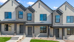 View of front of property featuring covered porch, stone siding, stucco siding, and a shingled roof