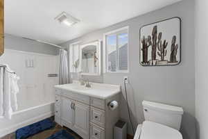 Bathroom featuring vanity, shower / bathtub combination with curtain, and dark tile patterned flooring