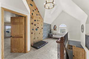 Carpeted bedroom featuring hanging lights, an accent wall, vaulted ceiling, and wooden walls