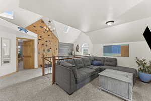 Living room with lofted ceiling, carpet, a skylight, and a chandelier