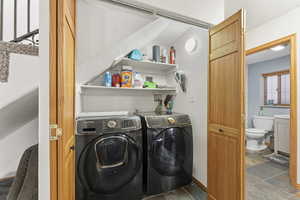Laundry area featuring separate washer and dryer and dark stone finish floors