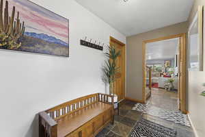 Hall with baseboards and stone tile floors