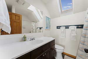 Bathroom with vanity, a shower with curtain, and lofted ceiling