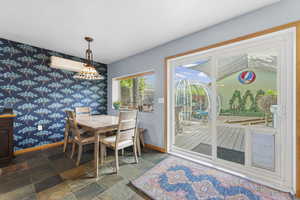 Dining area with stone tile flooring, wallpapered walls, and an accent wall