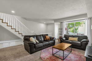 Living area featuring carpet flooring, a textured ceiling, and recessed lighting