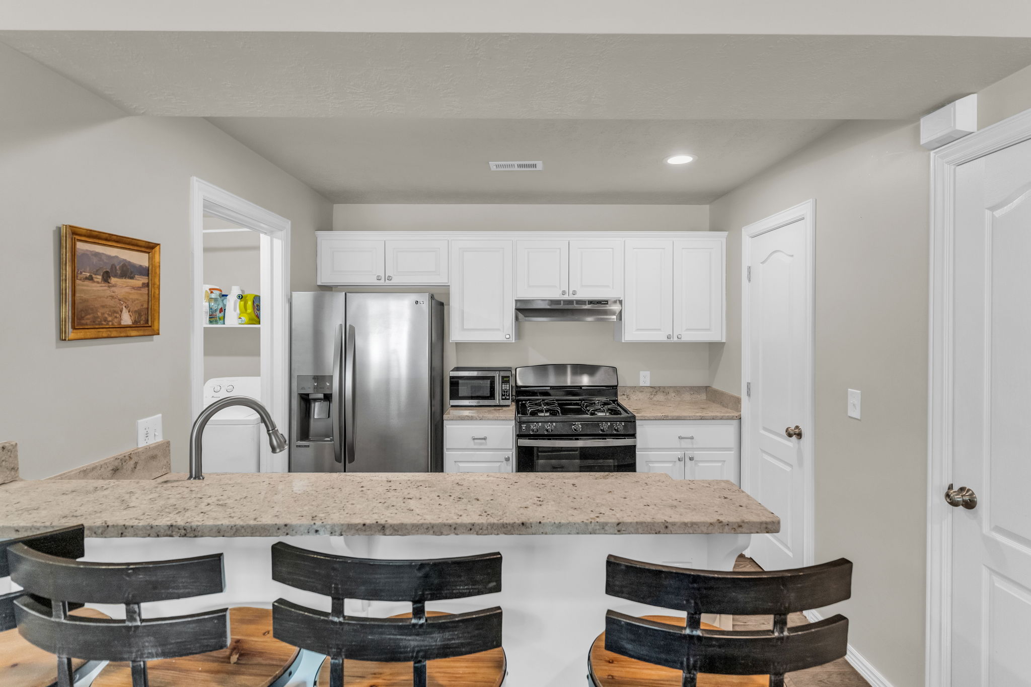 Kitchen with stainless steel appliances, a breakfast bar area, a peninsula, white cabinets, and recessed lighting