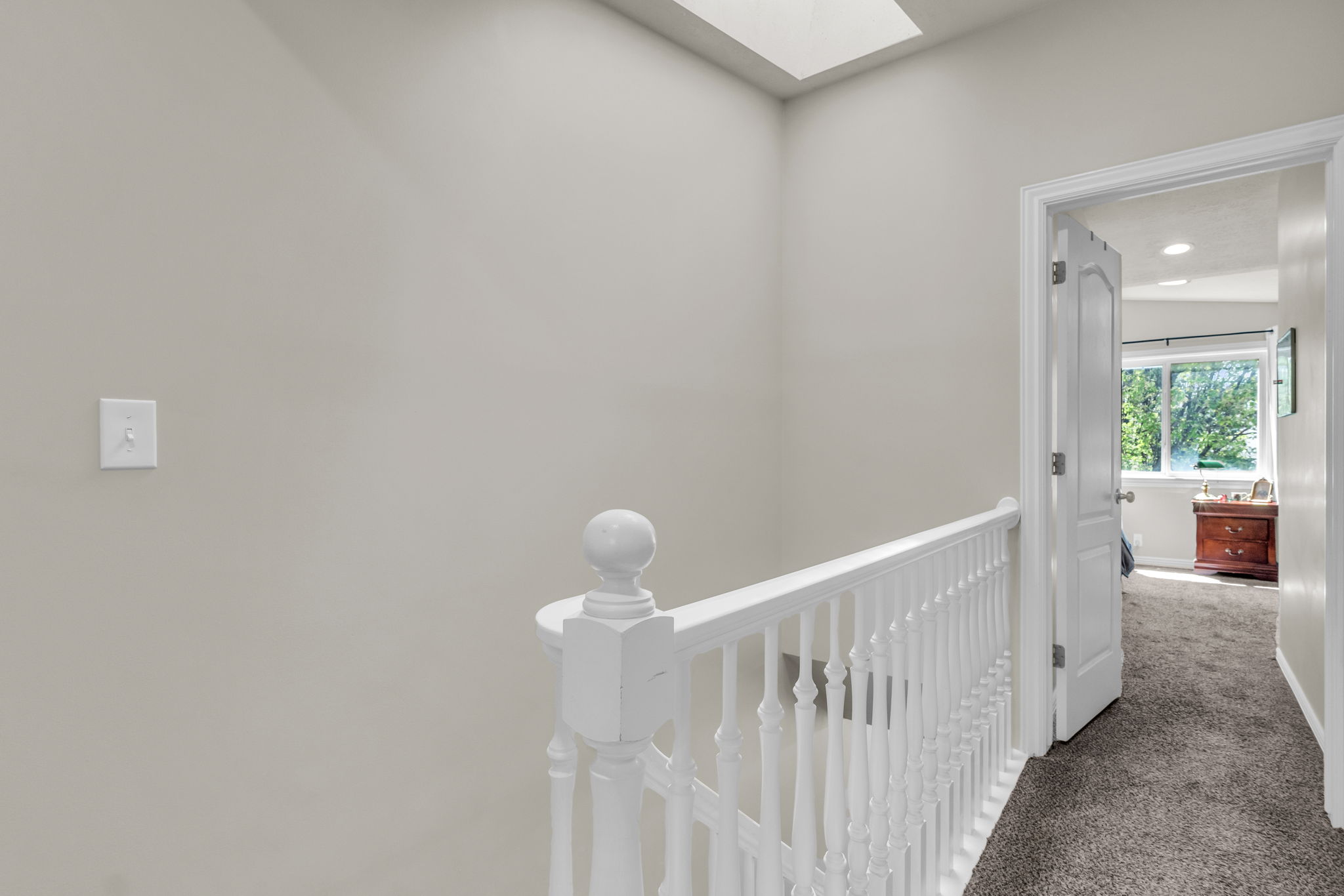 Corridor with a skylight, carpet floors, and an upstairs landing