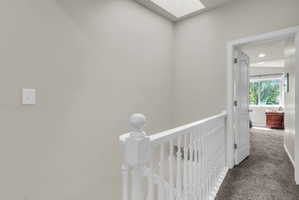 Corridor with a skylight, carpet floors, and an upstairs landing