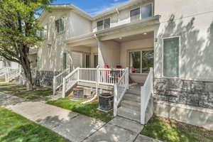 View of front of house with stucco siding, stone siding, and a porch