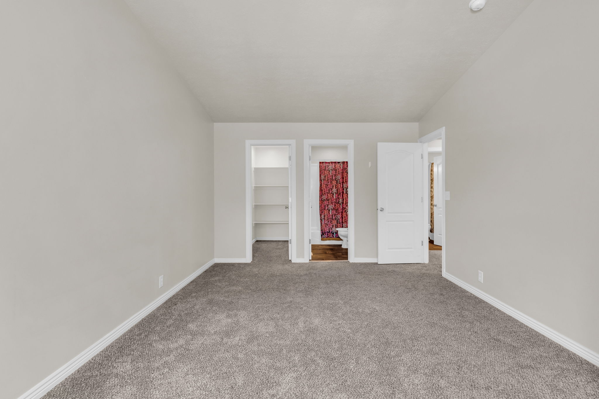 Unfurnished bedroom featuring a walk in closet, connected bathroom, and carpet