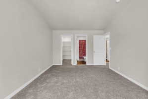 Unfurnished bedroom featuring a walk in closet, connected bathroom, and carpet