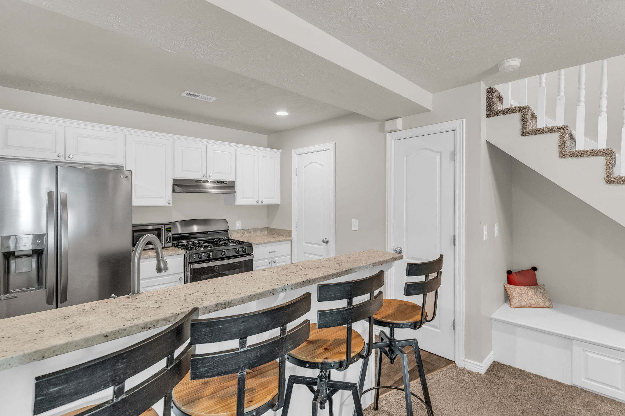 Kitchen with stainless steel appliances, white cabinetry, light stone countertops, a breakfast bar area, and recessed lighting