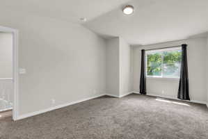 Unfurnished room featuring carpet floors and lofted ceiling