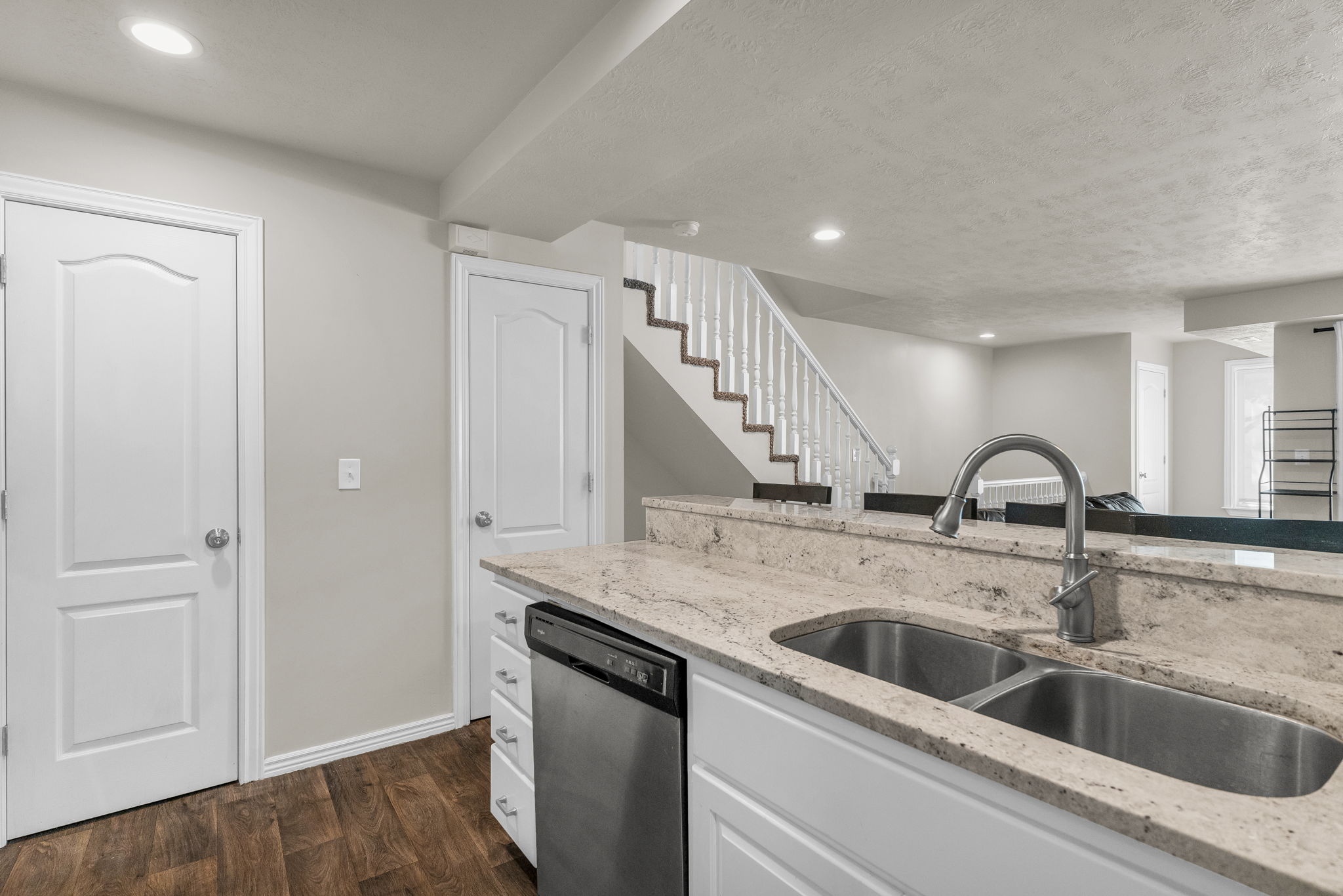 Kitchen with recessed lighting, white cabinets, light stone countertops, dark wood-style flooring, and stainless steel dishwasher