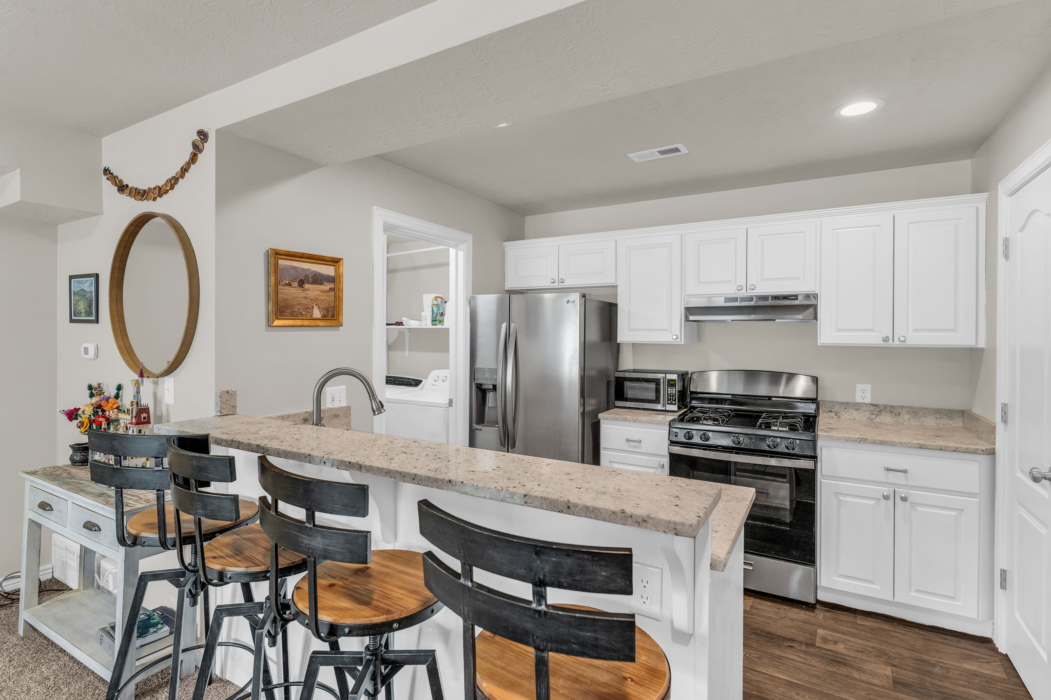 Kitchen with white cabinetry, stainless steel appliances, a breakfast bar, light stone countertops, and recessed lighting