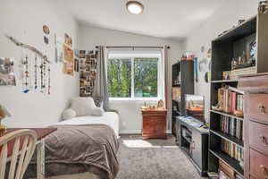 Carpeted bedroom with lofted ceiling and baseboards