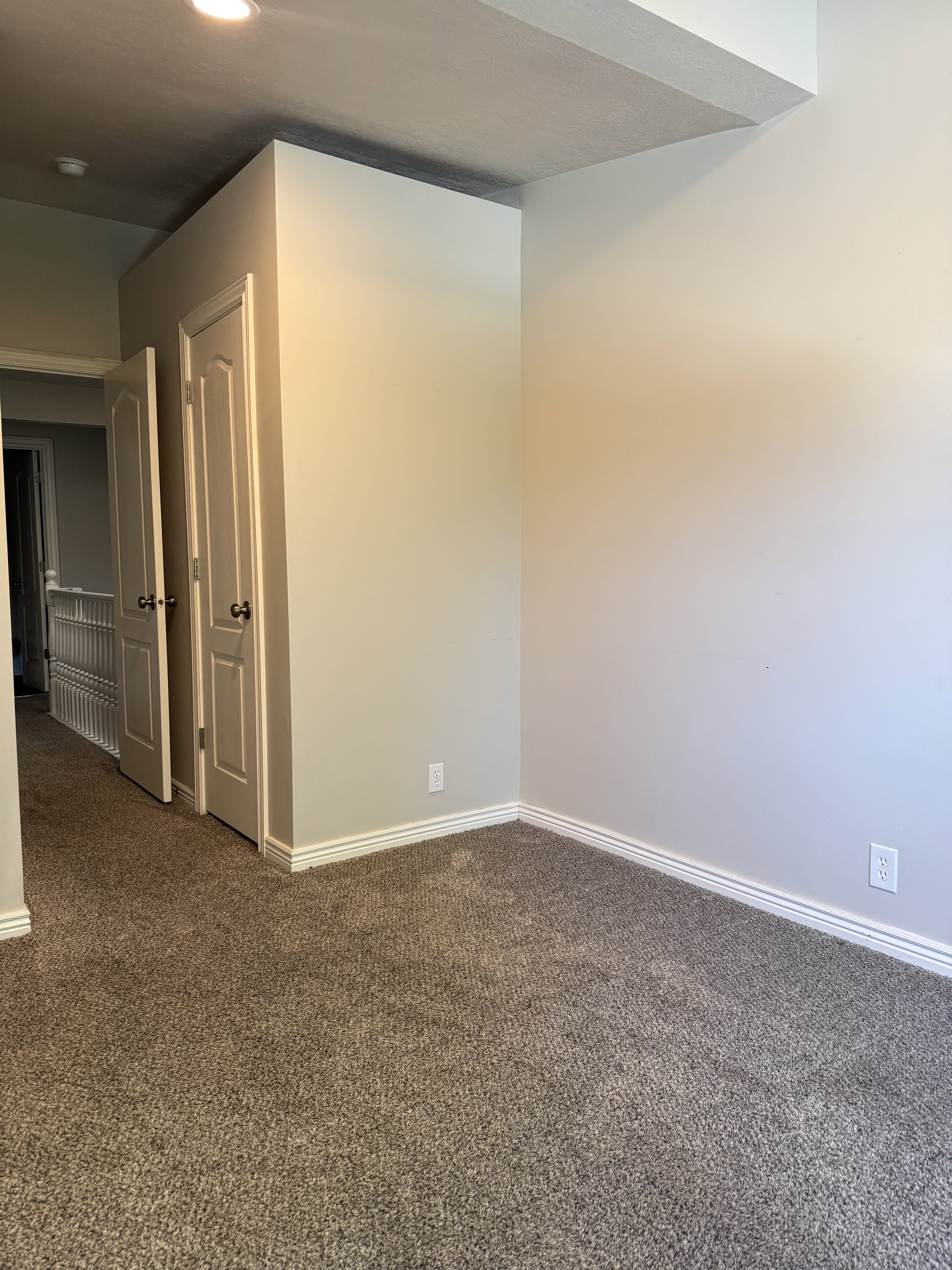 Plush, neutral-toned carpeting extends throughout, complemented by white baseboards and neutral wall finishes