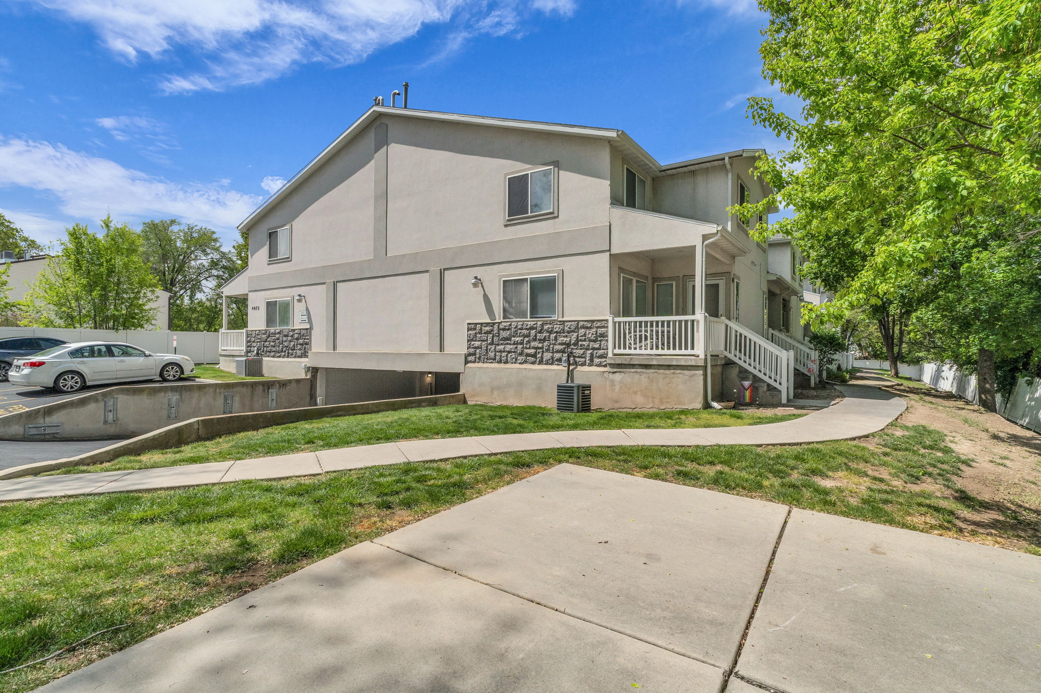 View of front of house with stucco siding, a porch, a front lawn, and stone siding