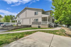 View of front of house with stucco siding, a porch, a front lawn, and stone siding