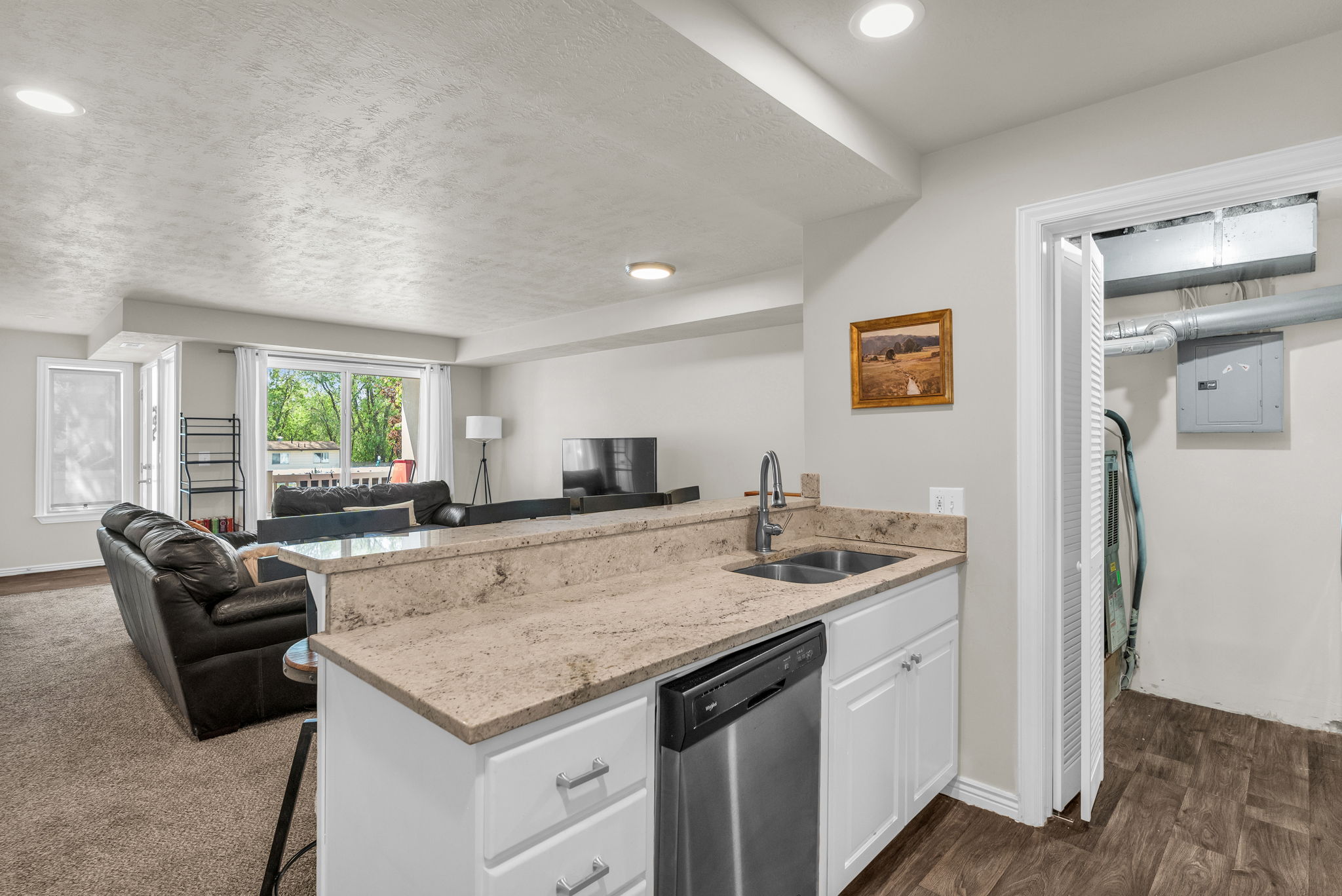 Kitchen with a peninsula, a breakfast bar area, white cabinets, open floor plan, and light stone counters