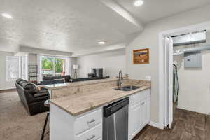 Kitchen with a peninsula, a breakfast bar area, white cabinets, open floor plan, and light stone counters