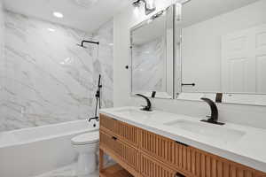 Bathroom featuring light marble finish floors, double vanity, and a combined bath / shower with marble appearance