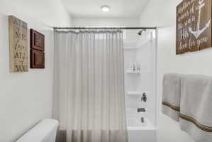 Bathroom featuring shower / tub combo with curtain and toilet