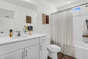Bathroom featuring shower / tub combo, vanity, and dark wood-style flooring