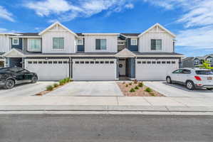 View of front of house featuring board and batten siding, an attached garage, driveway, and a residential view