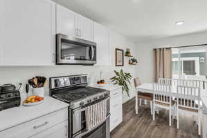 Kitchen featuring stainless steel appliances, white cabinets, and dark wood finished floors