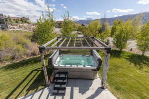 View of patio with a mountain view and a hot tub