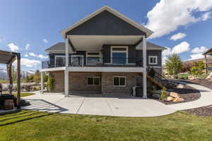 Back of property featuring a balcony, a lawn, a mountain view, and stucco siding