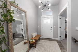 Foyer with suspended lighting, light wood finished floors, and vaulted ceiling