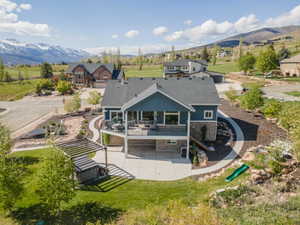 Rear view of house featuring stone siding, a patio, a balcony, and a mountain view