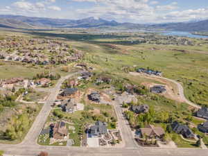 Aerial view of property and surrounding area featuring nearby suburban area and a water and mountain view
