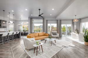 Living room featuring light wood-style flooring, hanging lights, and ceiling fan