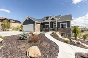 Craftsman house with a porch, stone siding, concrete driveway, and a garage