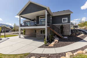 Rear view of property with stone siding, stucco siding, a mountain view, and a balcony