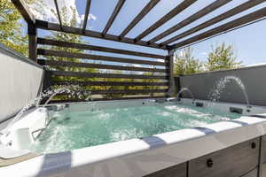 View of swimming pool with a hot tub and a pergola