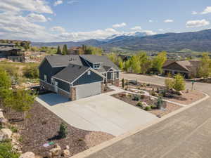 View of front facade with board and batten siding, stone siding, concrete driveway, a garage, and a mountain view