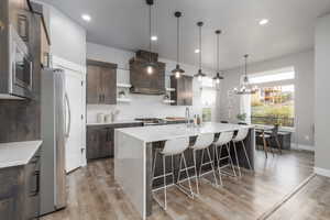 Kitchen with open shelves, light stone countertops, dark wood finish cabinetry, stainless steel appliances, and a large island