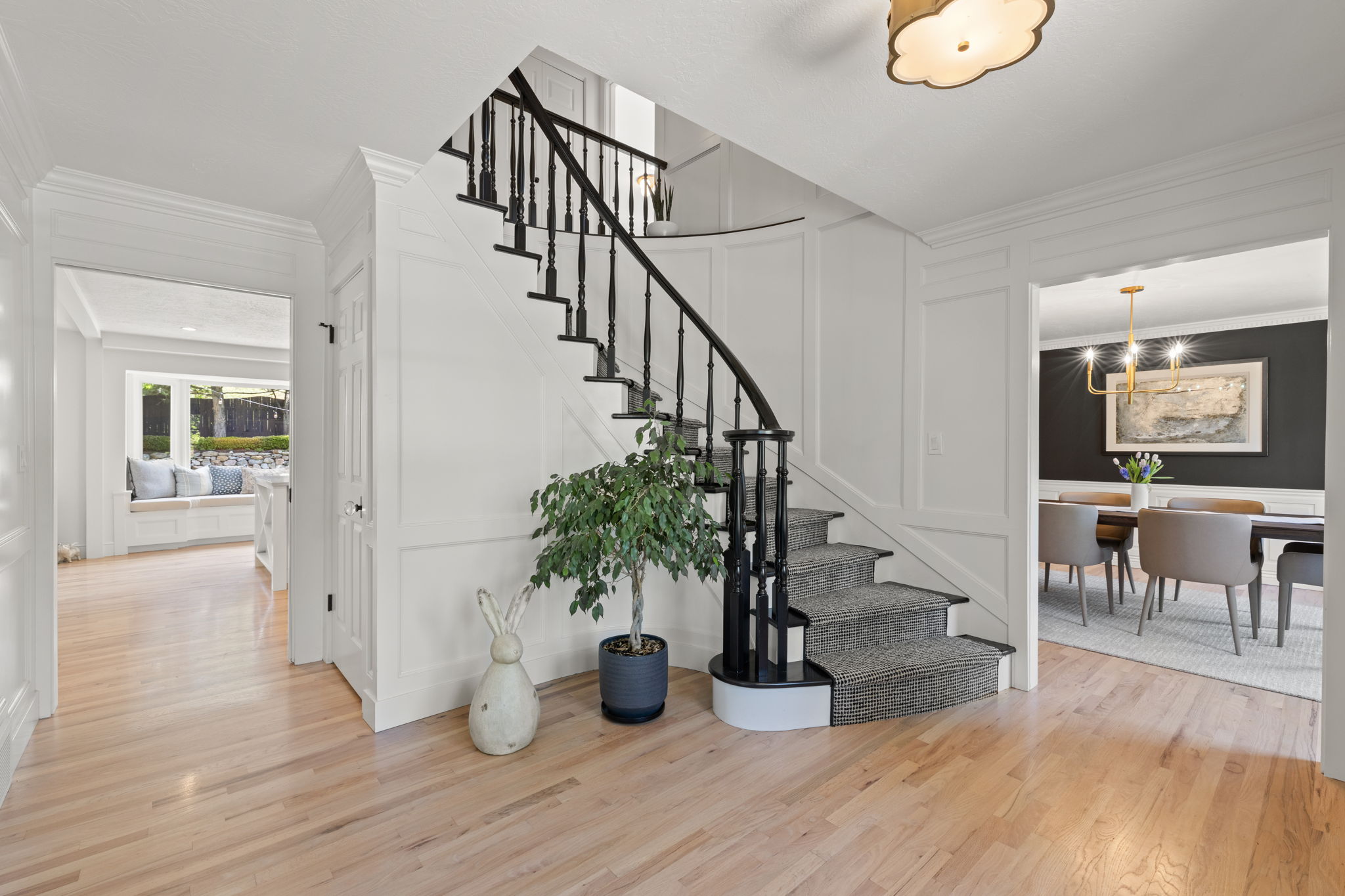 Stairway with a decorative wall, wood finished floors, and ornamental molding