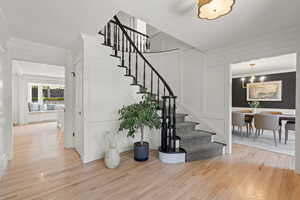 Stairway with a decorative wall, wood finished floors, and ornamental molding