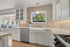 Kitchen featuring glass fronted cabinets, light stone countertops, white cabinetry, range with gas cooktop, and a textured ceiling