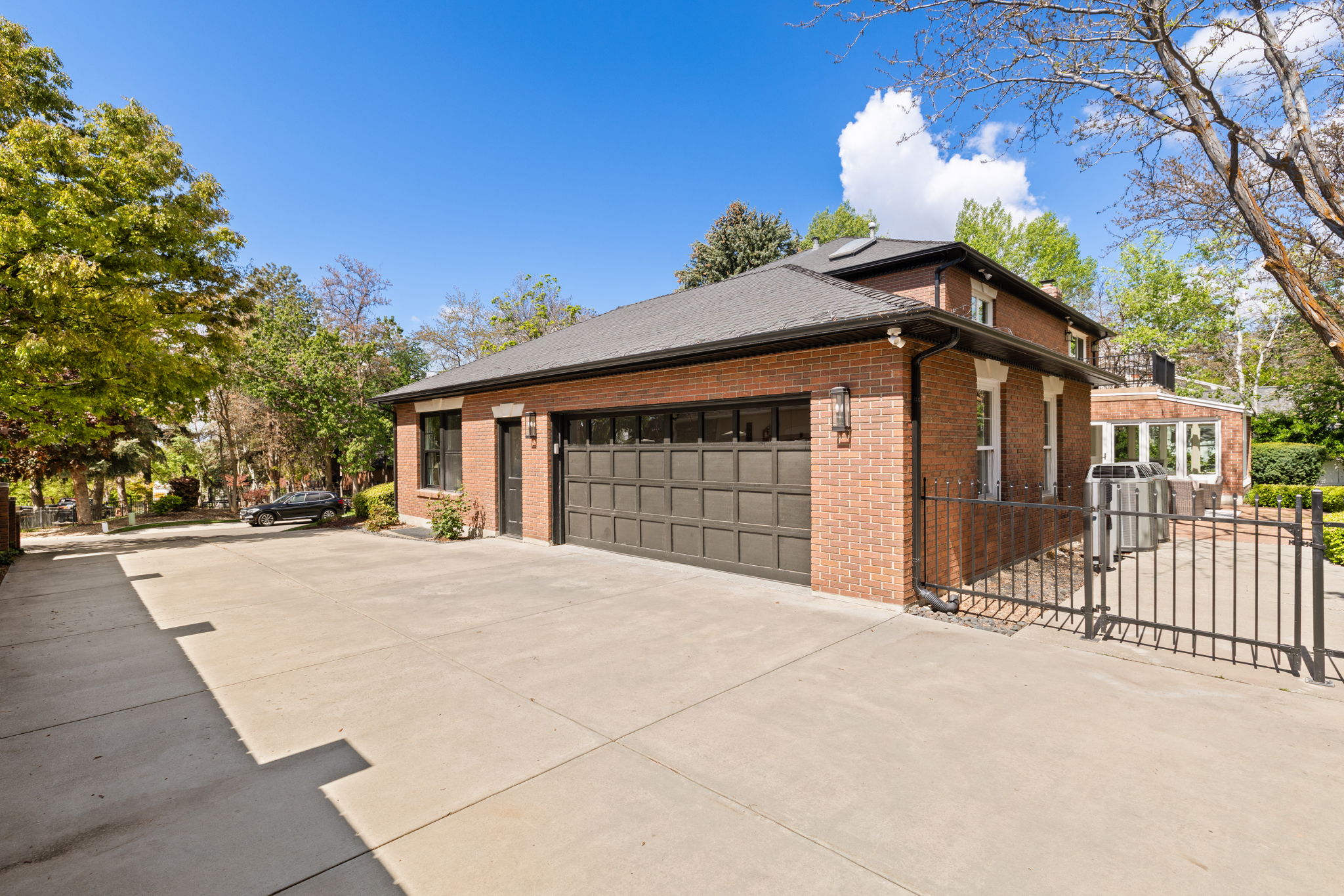 View of property exterior with concrete driveway, brick siding, a gate, a garage, and a chimney