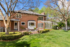 Back of property featuring a sunroom, an outdoor living space, a yard, and brick siding