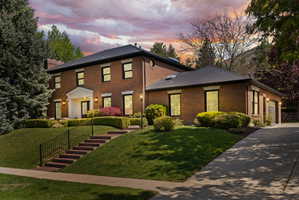 Colonial house with brick siding, a front lawn, and driveway