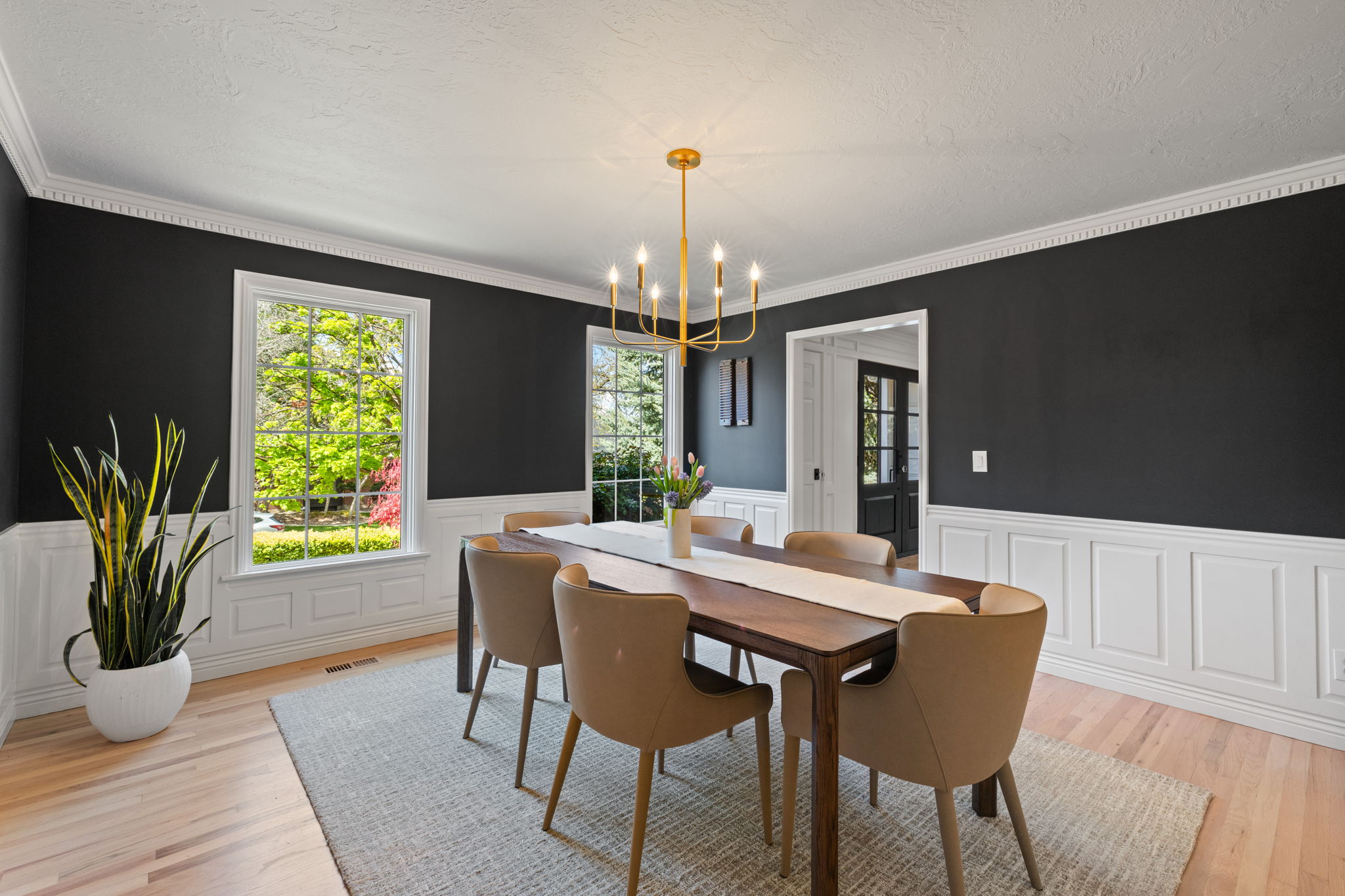 Dining room with a chandelier, wainscoting, light wood finished floors, crown molding, and a textured ceiling